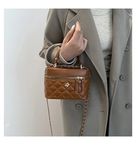 Close-up of quilted brown leather bucket bag with gold flower logo and dual zippers