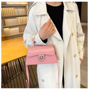 Sac bandoulière rose brillant avec fermoir rotatif en métal dans un intérieur moderne