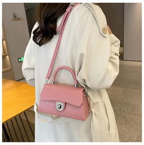 Sac boîte rose brillant avec fermoir rotatif argenté porté par un mannequin femme