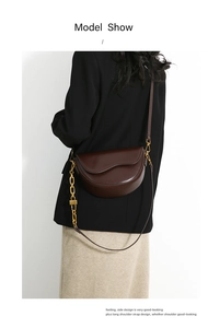 Deep brown saddle bag with golden chain and leather strap worn by a model