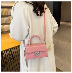 Sac à main rose avec fermoir argenté porté avec un trench-coat classique