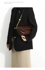 Detail of deep brown saddle bag with gold chunky chain strap and lock on a model