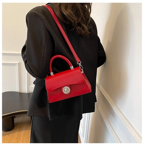 Sac boîte rouge en cuir avec fermoir argenté sur blazer noir pour un look élégant