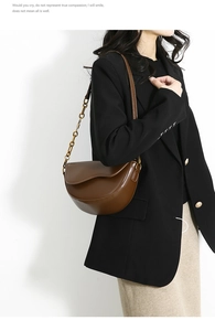 Close-up of brown matte saddle bag with vintage gold chain strap on a model