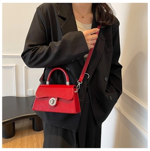 Détail du sac à main rouge brillant en cuir avec fermoir métallique ondulé élégant