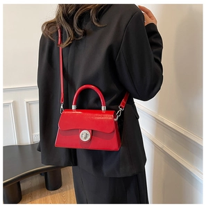Détail du sac boîte en cuir verni rouge brillant avec fermoir rotatif argenté et poignée