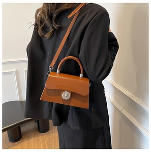 Détail du sac à main marron caramel avec fermoir rotatif argenté et structure rigide chic