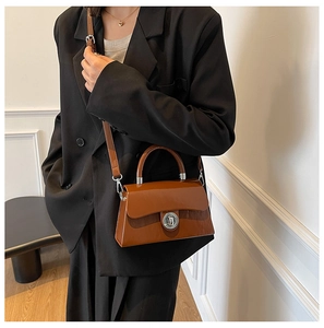 Sac boîte en cuir marron avec fermoir argenté porté par un mannequin stylé