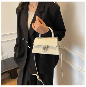 Détail du sac boîte en cuir crème avec fermoir rotatif en métal et fine bandoulière