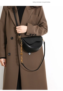 Detail view of the elegant black leather saddle bag with gold chain and side design