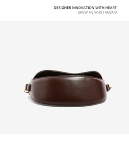 Close-up of a vintage dark brown leather saddle bag with refined gold buckle detail