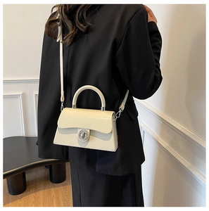 Détail du sac boîte en cuir crème minimaliste avec fermoir rotatif argenté et poignée haute