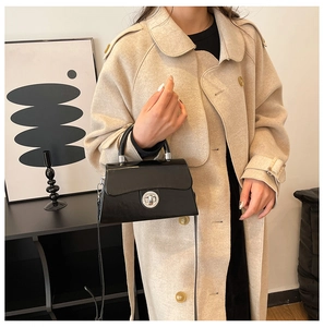 Détail d'un sac à bandoulière en cuir noir minimaliste avec fermoir argenté par un mannequin