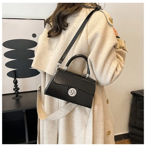 Mannequin portant un sac bandoulière en cuir noir mat avec fermoir rotatif argenté rond
