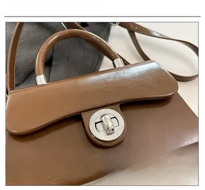 Gros plan détaillé du fermoir métallique rond sur un sac boîte en similicuir marron