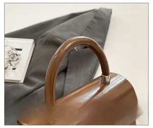 Détail de la poignée en cuir brillant marron avec coutures fines et ferrures argentées