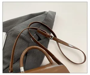 Vue détaillée de la bandoulière réglable et boucle argentée du sac vintage marron