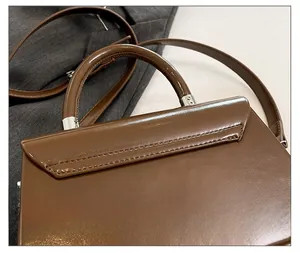 Gros plan du sac à main marron brillant avec détails métalliques et coutures précises