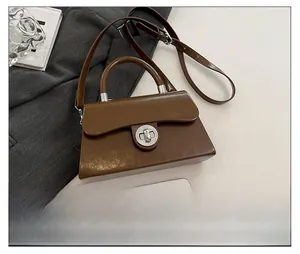 Sac bandoulière marron avec fermoir argenté et smartphone pour référence de taille réelle