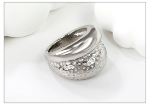 Detail view of a chunky silver stainless steel ring with hammered texture on a white stand