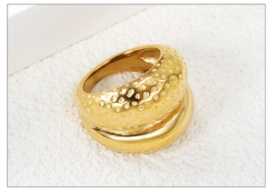 Macro detail of a wide gold stainless steel ring with hammered and mirror finish