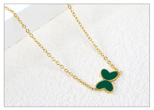 Gros plan d'un collier papillon doré avec des ailes en émail vert en forme de cœur