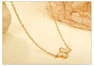 Détail d'un pendentif papillon doré avec incrustation blanche sur une chaîne fine