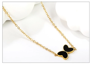 Gros plan du collier papillon doré avec incrustation noire et maillons de chaîne croisés