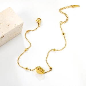 Bracelet de cheville en acier inoxydable doré avec pendentif cœur sur fond blanc