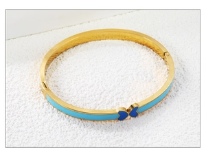 Detail of gold-plated bangle with sky blue enamel and a blue butterfly hinge closure