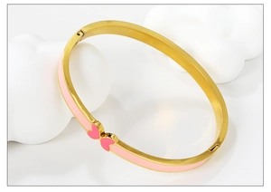 Detail of gold-plated bangle featuring pink enamel coating and double heart motif
