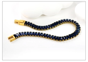 Detail eines vergoldeten Tennisarmbands mit blauen Kristallen und Klappverschluss