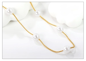 Close-up of elegant pearl and gold bead necklace on minimalist white stone display