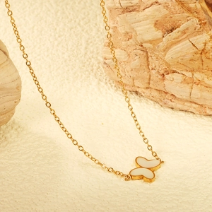 Collier élégant avec pendentif papillon doré et ailes en émail blanc sur une pierre brute