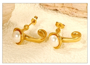 Détail macro de boucles d'oreilles dorées en C avec perles blanches sur pierre