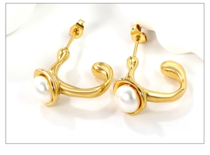 Macro d'une paire de boucles d'oreilles en C dorées avec perles blanches rondes