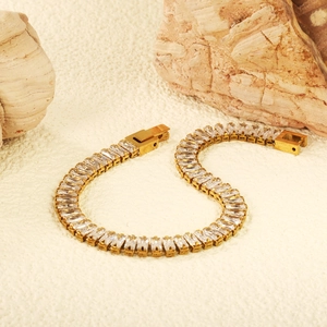 Luxuriöses Tennisarmband in Gold mit rechteckigen Zirkonia auf Stein-Hintergrund