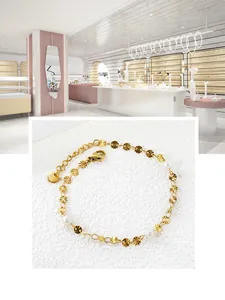 Détail d'un bracelet en acier inoxydable doré avec disques gaufrés et perles blanches