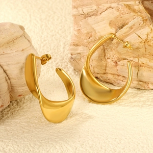 Vue détaillée des boucles d'oreilles dorées ondulées sur une surface en pierre