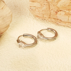 Eleganti orecchini a cerchio argento con zirconi a goccia su sfondo in pietra naturale