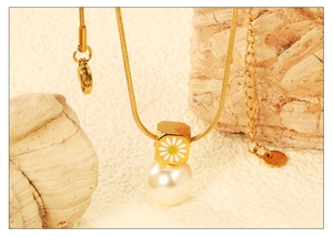 Détail macro du collier chaîne serpent dorée avec breloque marguerite et perle blanche