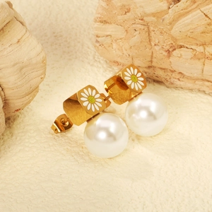 Boucles d'oreilles marguerites avec perles blanches posées sur un socle de pierre