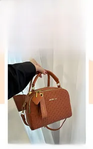 Detailed view of brown Boston bag featuring woven texture and gold hardware accents