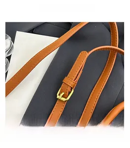 Detail of adjustable brown leather shoulder strap with golden metal buckle and stitching