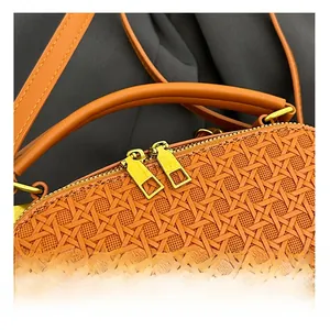 Detail view of smooth dual golden zippers and caramel woven texture on small square bag