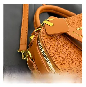 Detailed close-up of woven texture and premium gold hardware on the orange-brown bag