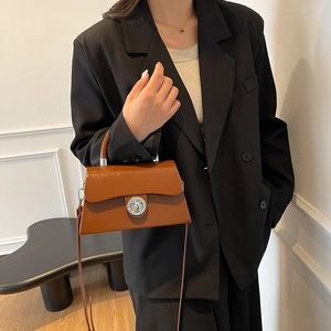 Sac boîte vintage en cuir marron avec fermoir argenté et poignée porté par mannequin