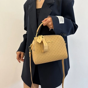 Beige woven textured handbag with metal logo and shoulder strap on navy blazer