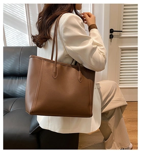 Detailed view of brown leather tote bag handle and stitching for office commuting