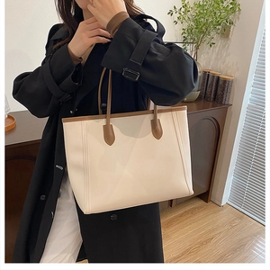 Close-up of a high-capacity cream tote bag with brown straps styled on a model's shoulder